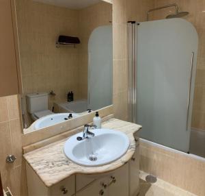 马德里Apartamento grande, 2 dormitorios, garaje gratis的一间带水槽、浴缸和镜子的浴室