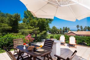 雷夫卡达镇Villagio的庭院配有桌椅和遮阳伞。