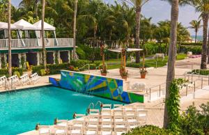 迈阿密海滩金普顿赛康贝酒店的一个带白色椅子的游泳池,一个度假村