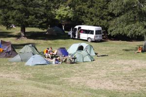 罗托鲁瓦罗托鲁阿温泉假日公园酒店的一群人坐在田野里,有帐篷