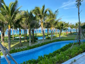 金兰市Seaview Arena Cam Ranh Nha Trang hotel near the airport的棕榈树和大海的游泳池