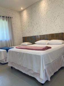 普拉杜Casa de praia Prado Ba Doces magnólias的一间卧室配有两张带白色床单和枕头的床。