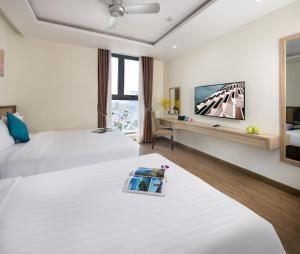 芽庄Sata Hotel的酒店客房设有两张床和一台平面电视。