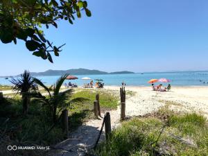 邦比尼亚斯Residencial Bombinhas Pé na Areia的一片拥有人员和遮阳伞的海滩和水域