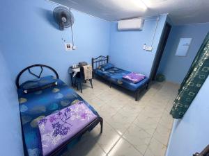 Kampong Alor GajahIkhlas Roomstay的蓝色的客房配有两张床和一张桌子