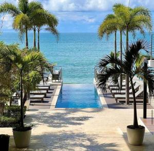 圣卡洛斯Charming Zen-style Beach apartment at Punta Caelo的拥有游泳池、棕榈树和海洋的度假胜地