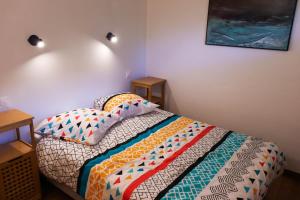 珀蒂蒂勒LE TUIT TUIT的一间卧室配有一张带色彩缤纷的被子和枕头的床。