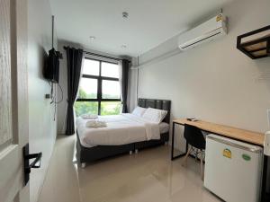 Ban MaiLife Hotel Rong Khun的一间卧室配有一张床、一张书桌和一个窗户。