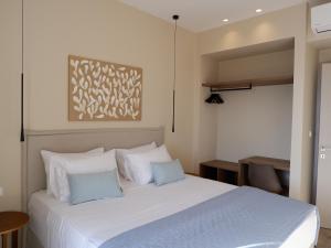 AchílleionKaiser Luxury Suites的卧室配有带蓝色枕头的大型白色床