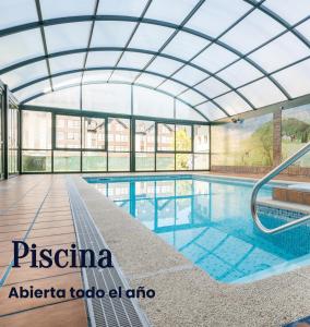 维耶拉El Refugio de Aran Vielha Aparthotel的一个带玻璃天花板的游泳池和一个室内游泳池