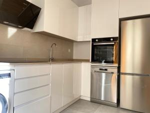 塞维利亚Hispalis Menendez Pelayo的厨房配有白色橱柜和不锈钢冰箱