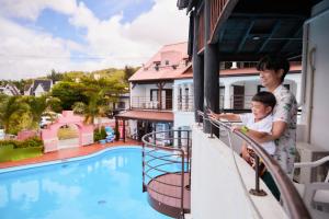 恩纳冲绳池度假酒店的有一个妇女和儿童,在阳台上看游泳池
