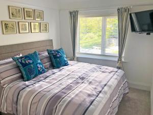 赫斯沃尔May Escape的一间卧室配有一张带蓝色枕头的床和一扇窗户。