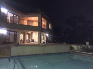 约翰内斯堡Views for Africa的一座在晚上设有游泳池的大房子