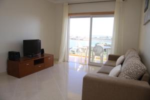 波尔蒂芒Apartamento Arade Portimao的带沙发和电视的客厅以及阳台。