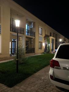 TürkistanKERUEN SARAY APARTMENTS 6/2的夜间停在大楼前的汽车