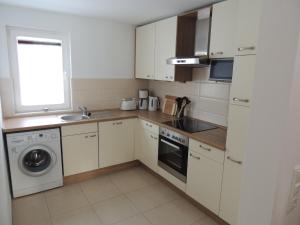 格洛韦Haus Annette的厨房配有白色橱柜、水槽和洗碗机。