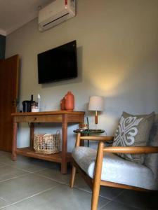 里贝朗克拉鲁Pousada Villa Paraizo的客厅配有椅子和墙上的电视