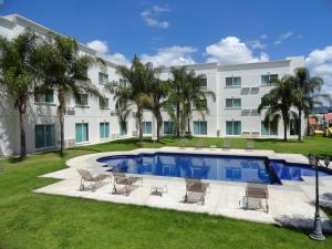 莱昂Hotel Real de Minas Bajio的一座大建筑,在院子里设有游泳池和椅子