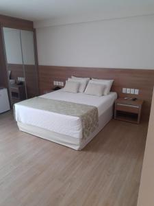 多明戈斯马丁斯Vista Azul Apart Hotel - Vista Pinheiros的卧室配有一张带白色床单和枕头的大床。