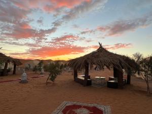 梅尔祖卡Merzouga Camp & Desert Activities的沙漠中的小屋,背景是日落