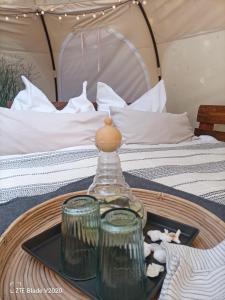 巴姆施泰特Glamping Altes Pastorat的床上桌子上装有瓶子和玻璃杯的托盘