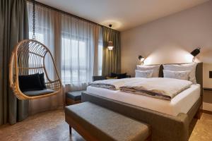 萨尔茨堡Cocoon Salzburg的配有一张床和一把椅子的酒店客房