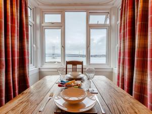 昆斯费里Forth Reflections的带窗户的客房内的木桌,配有盘子和酒杯