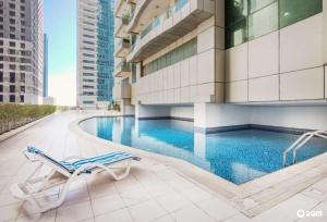 迪拜Dream Inn Apartments - Marina Pinnacle的酒店游泳池设有椅子,酒店大楼