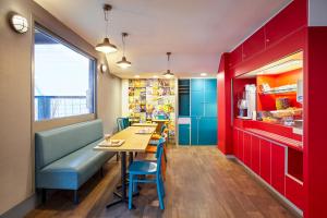 科当hotelF1 Lorient的餐厅设有红色和蓝色的橱柜以及桌椅