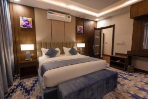 艾卜哈Aman Hotel Suites的酒店客房设有一张大床和两盏灯。