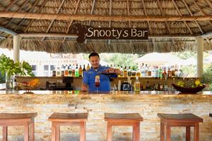 珀拉什奇亚Sirenian Bay Resort -Villas & All Inclusive Bungalows的站在酒吧后面喝一杯的人