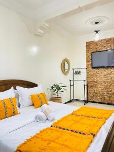 阿加迪尔darna surf house anza的一间卧室配有带橙色枕头的床和平板电视