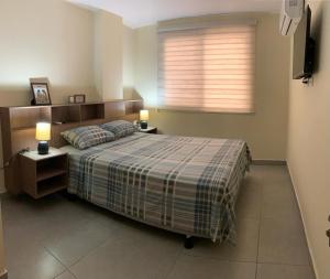瓜亚基尔Garzota Suites Gardens的一间卧室配有一张带两盏灯的床和一扇窗户。