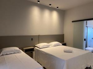 圣若昂-巴蒂斯塔-杜格罗里亚Pousada Pôr do Sol的一间设有两张带白色床单的床的房间