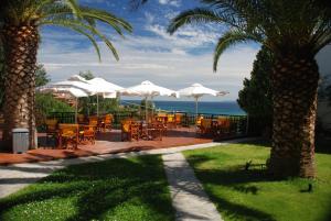 欧拉努波利斯斐罗克斯尼娜酒店的一个带桌子和白色遮阳伞的庭院和大海