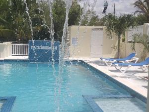 白豪斯Westmore Beach Villas Limited的游泳池里的喷泉,带两把蓝色椅子