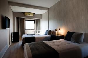 布宜诺斯艾利斯Believe Madero Hotel的酒店客房设有两张床和电视。