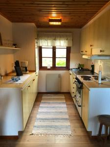 SävekullaSävekulla 208 "Lillekulla"的厨房铺有木地板,配有白色橱柜。