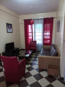达喀尔Appartement sympathique Jules Ferry.的客厅配有红色窗帘、沙发和椅子