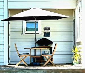 玛塔玛塔Okauia House, Matamata的一把桌子和两把椅子放在伞下