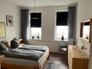 罗斯托克Schmuckstück im Herzen Rostocks mit grüner Oase的卧室配有一张床、一张书桌和窗户。