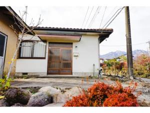 日光Second House Nikko - Vacation STAY 13408的一间白色的房子,有一道棕色的门和一些岩石