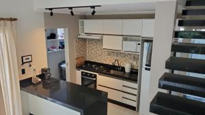 塞古罗港Casa da lagoa的厨房配有白色橱柜和黑色台面