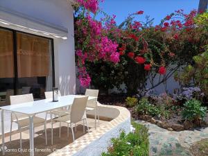 拉克鲁斯Schöne Wohnung in Puerto de la Cruz mit Garten.的鲜花庭院里的白色桌子和椅子