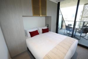 阿德莱德Realm Apartments by CLLIX的卧室配有带红色枕头的大型白色床