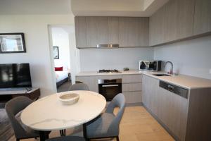 阿德莱德Realm Apartments by CLLIX的厨房配有桌子和桌椅