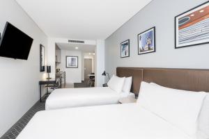 悉尼Holiday Inn & Suites Sydney Bondi Junction, an IHG Hotel的酒店客房设有两张床和电视。