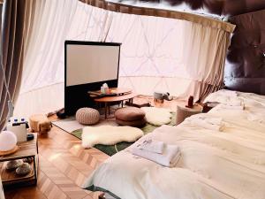 富士河口湖Necoana Glamping的客房设有两张床、一张桌子和屏幕
