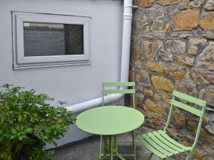 阿尼克Joellen Cottage的一张绿色桌子和两把椅子,靠墙